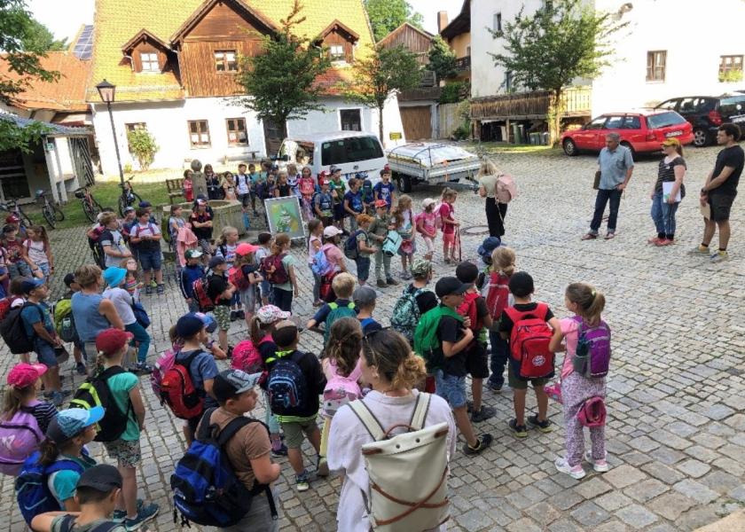 viele Kinder stehen in einem Hof, die Betreuer stehen vor Ihnen