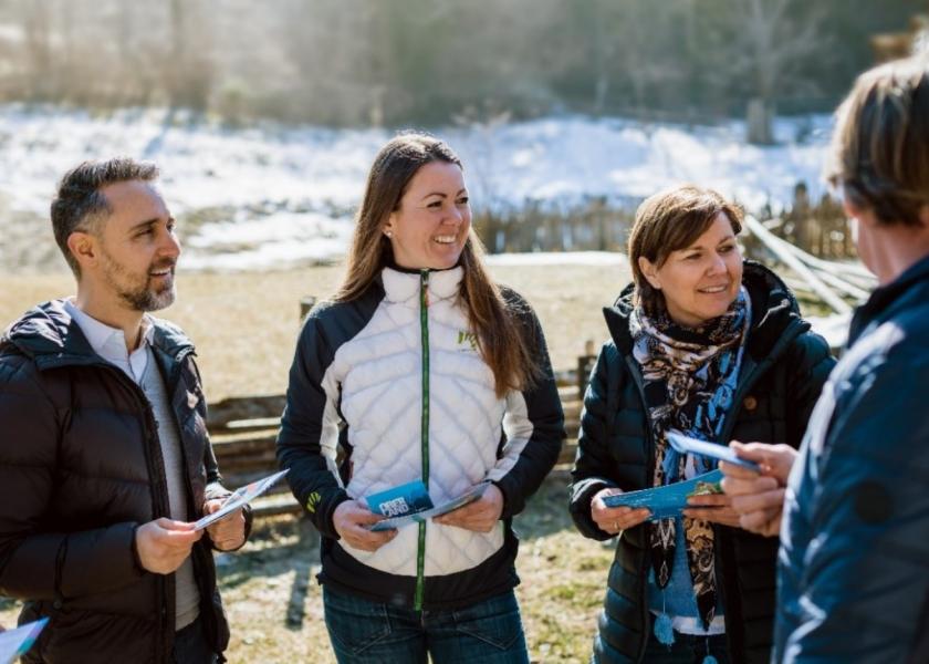 ein Mann und zwei Frauen stehen in der Natur (im Hintergrund ist Schnee sichtbar) und halten die OBERLANDCard in der Hand, auf der rechten Seite steht ein Mann mit dem Rücken zur Kamera mit Karte
