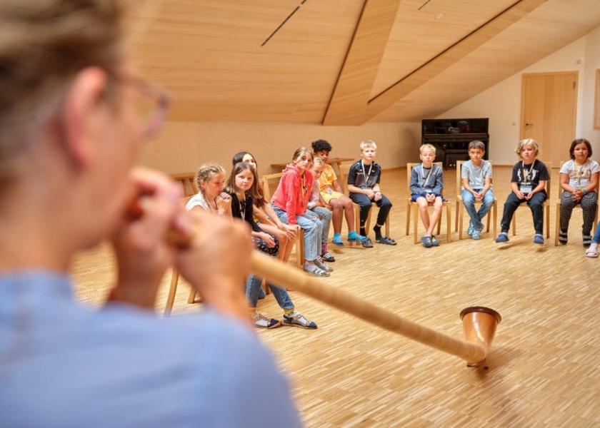 Mann spielt Didgeridoo und Kinder sehen zu