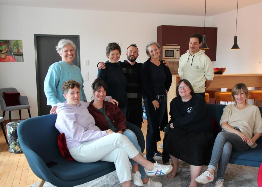 9 Menschen sitzen in bequemen Sesseln bzw. stehen dahinter