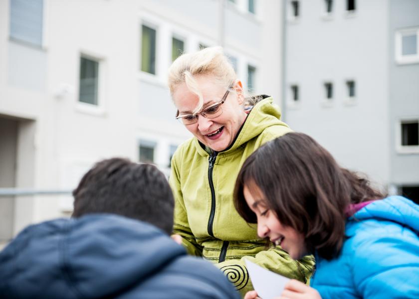 Frau im Gespräch mit zwei Kindern mit Migrationshintergrund