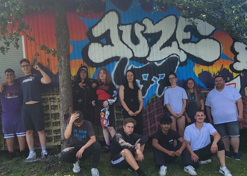 Gruppe Jugendlicher vor selbst gestalteter Graffitiwand 