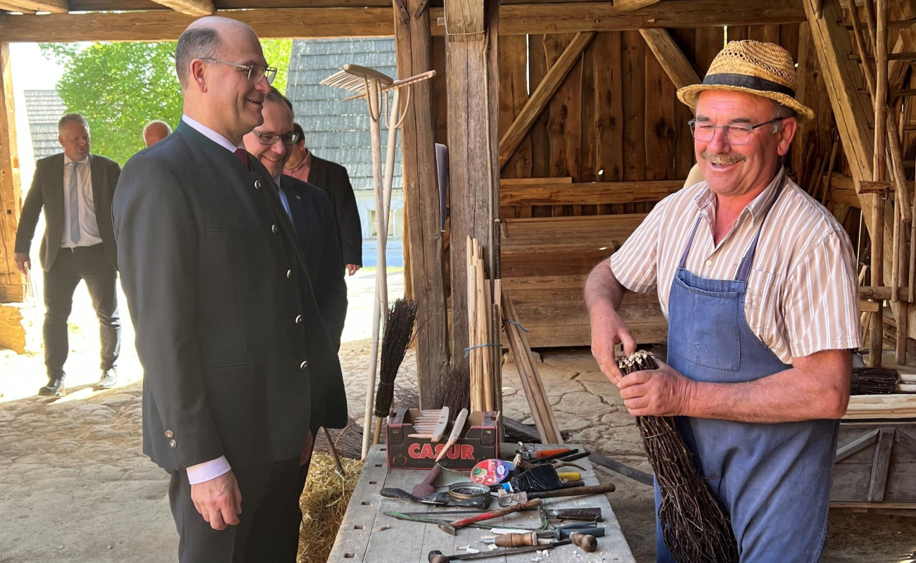 Heimatminister Füracker an Stand zu traditioneller Rechenherstellung 