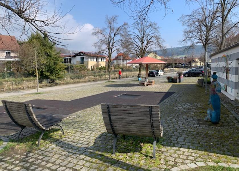 selbst gestalteter Platz mit zwei Holzliegen und Skulptur 